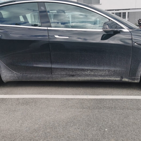 Zwarte Tesla Model 3 van opzij